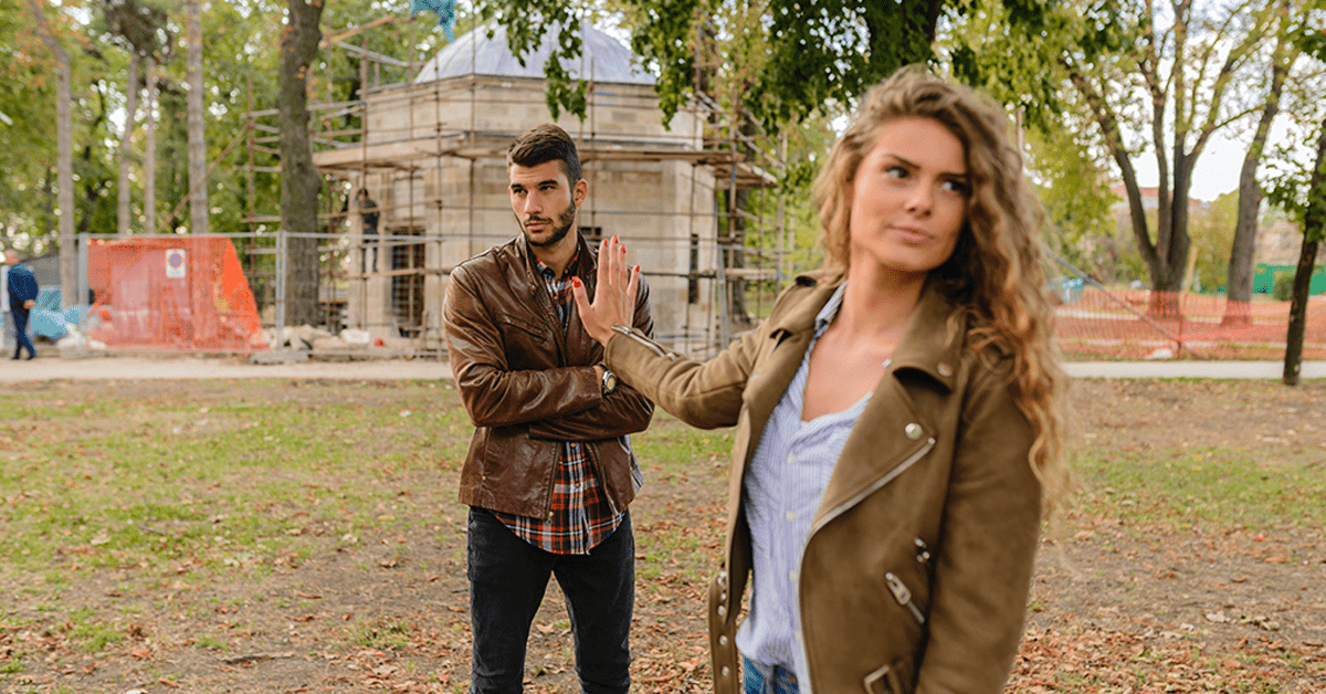 woman turning her back and holding up her hand to her boyfriend