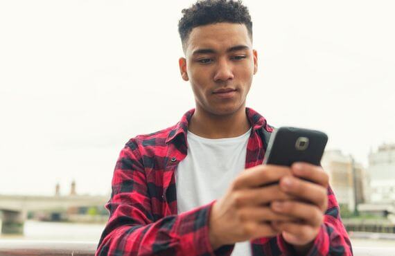 black man in a flannel shirt looking at his phone