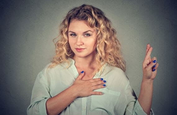 Women with hand over heart and fingers crossed thinking about online dating for Christians.