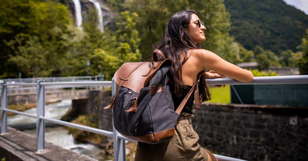 Woman with a backpack leaning on a railing that overlooks a river