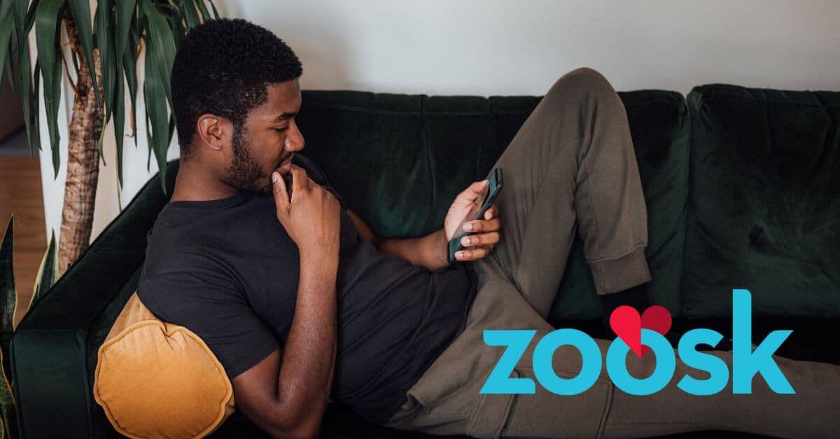 Man sitting on couch using zoosk dating app
